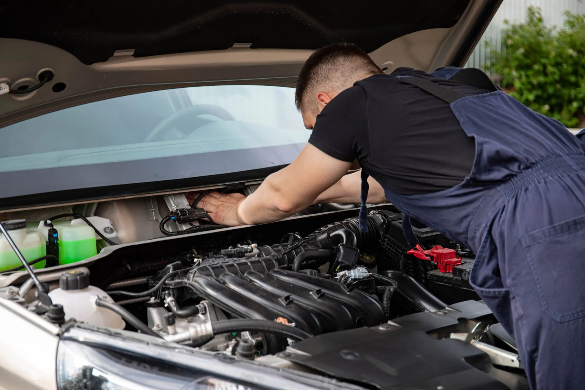 Inspector examining the engine bay of a used truck, checking belts, fluids and components