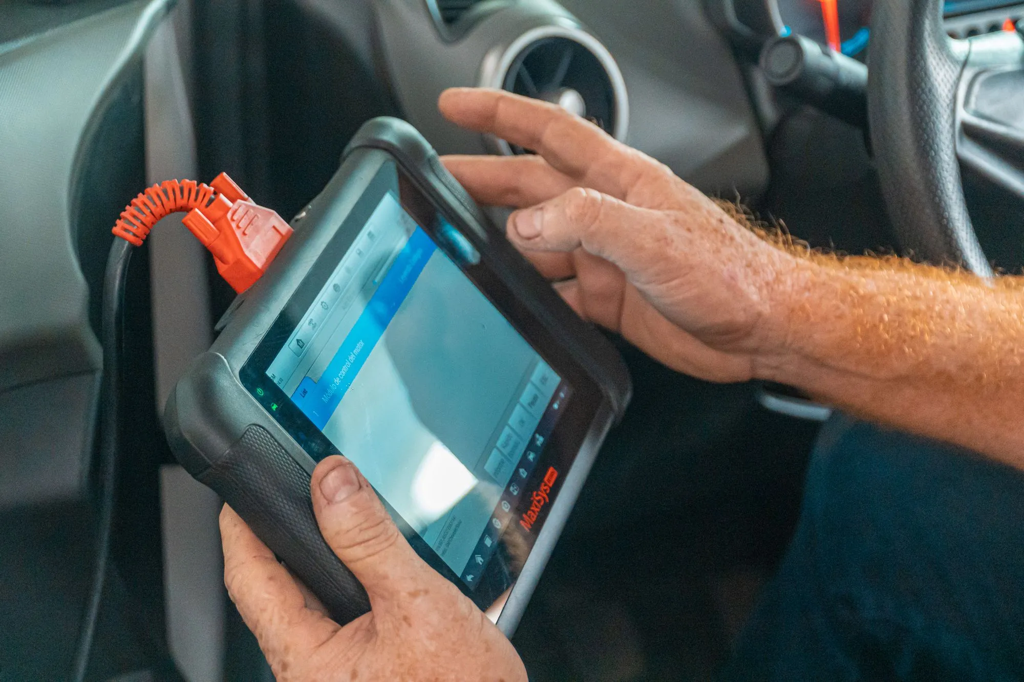 Diagnostic scan tool connected to a vehicle's OBD port reading system fault codes
