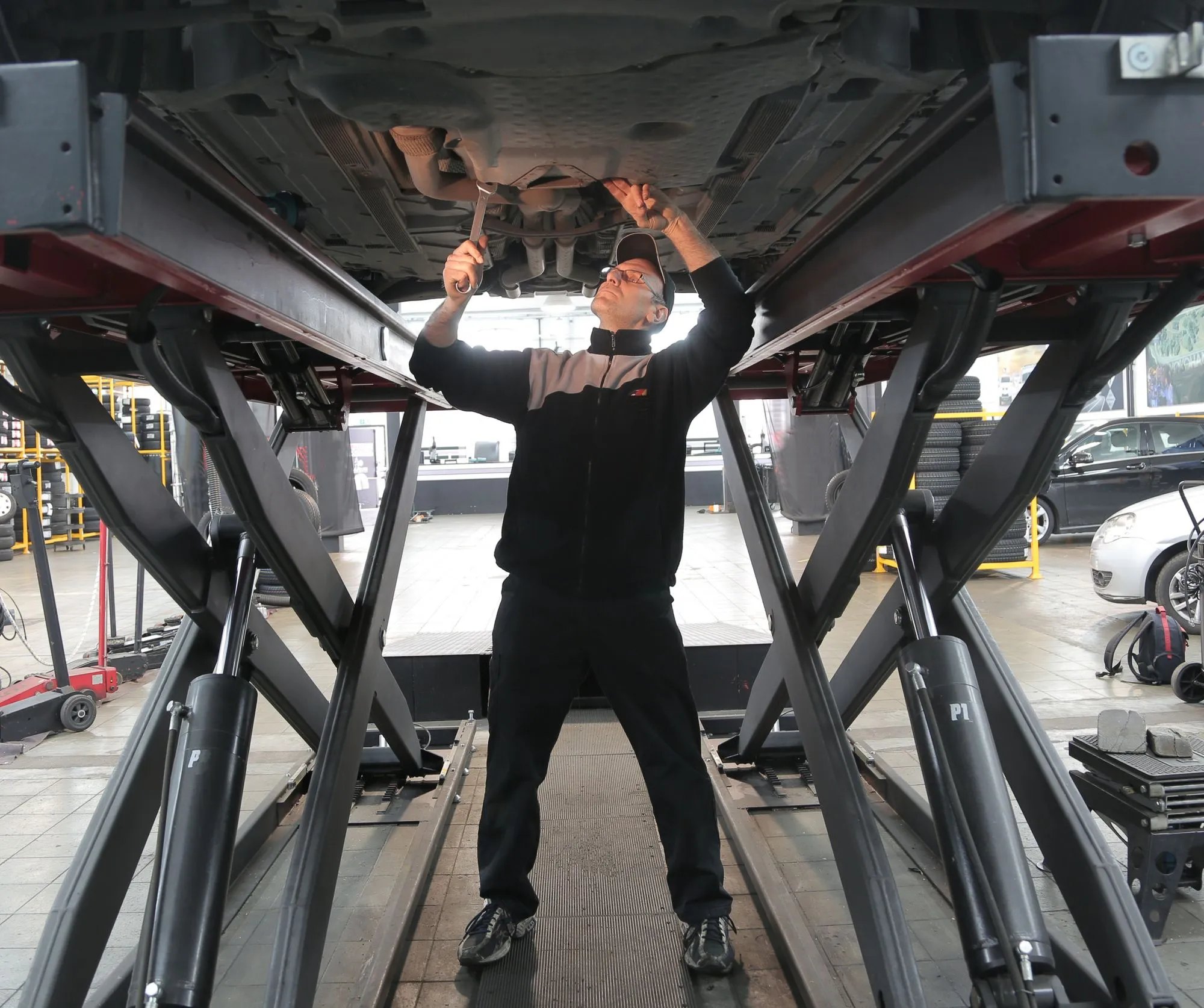 Inspector using a flashlight to examine the undercarriage of a used vehicle